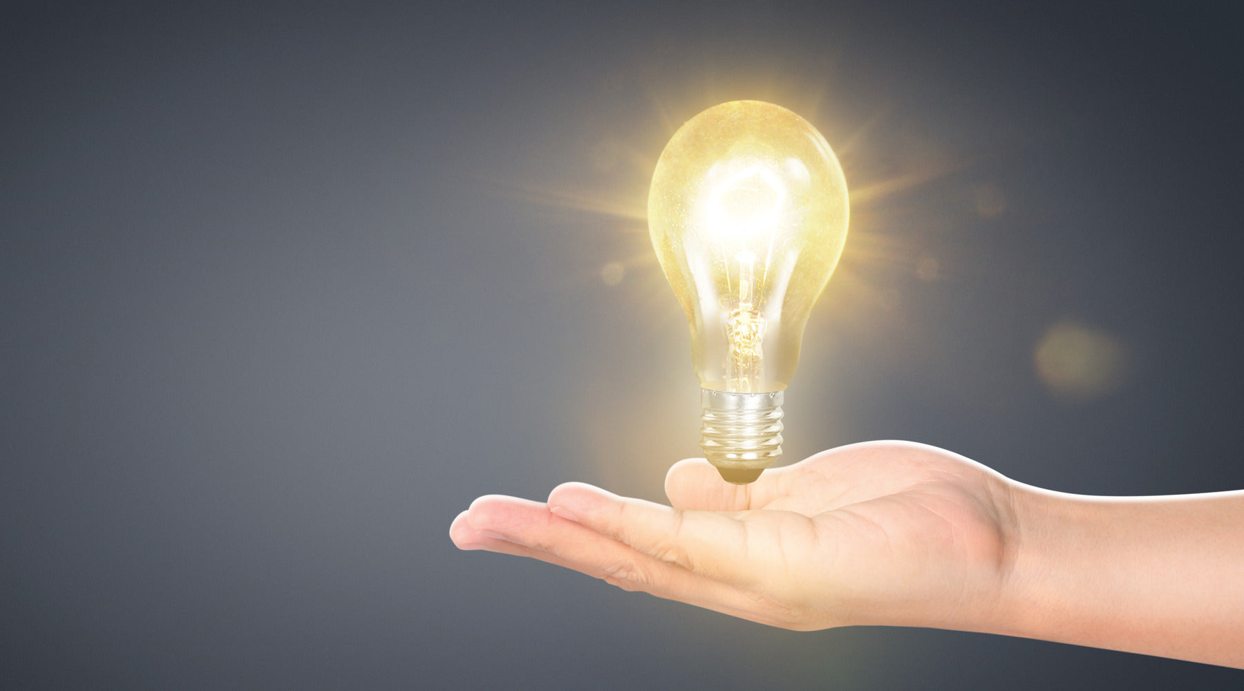 Hand holding illuminated LED A19 bulb with E26 base